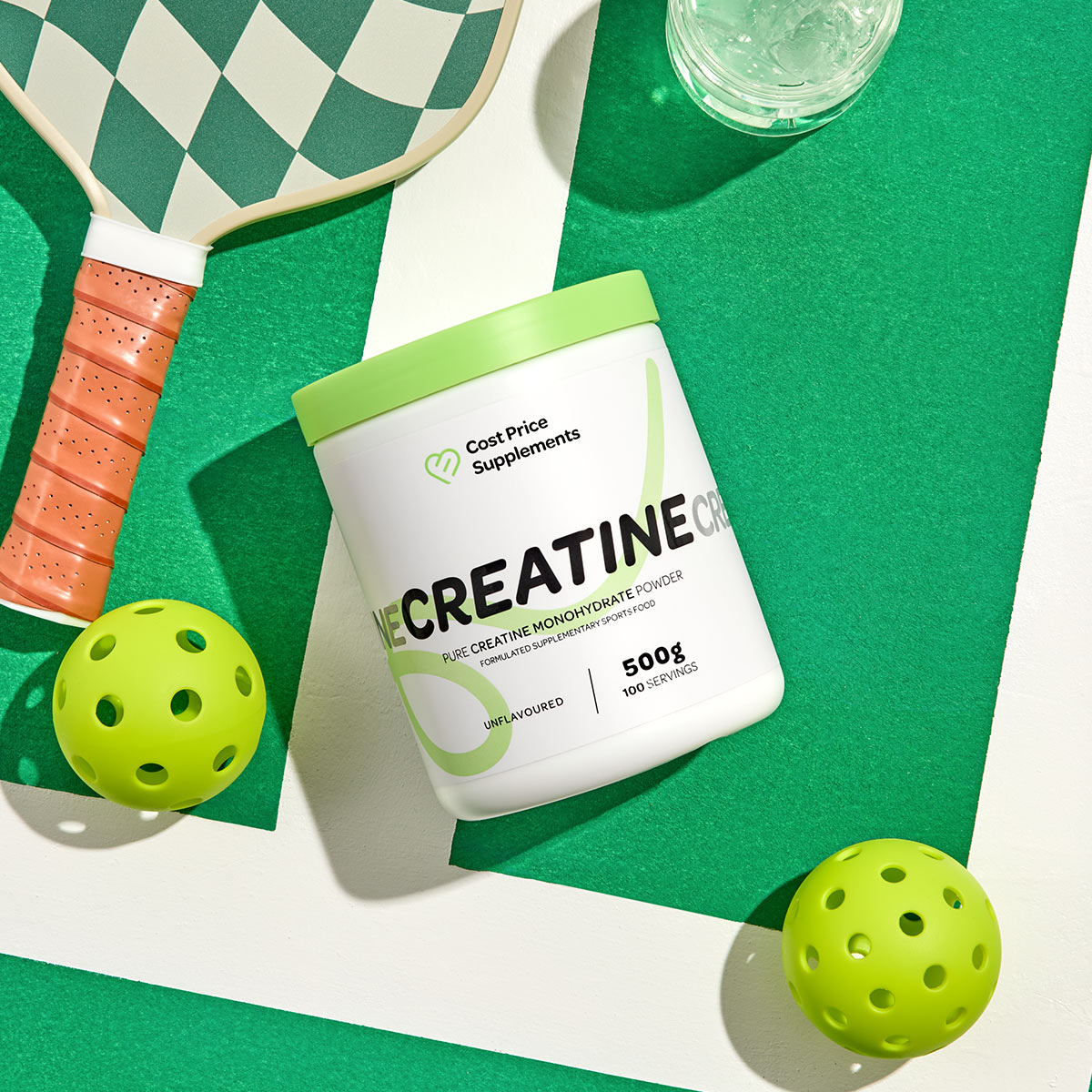 Creatine supplement container with pickleball equipment on a green surface
