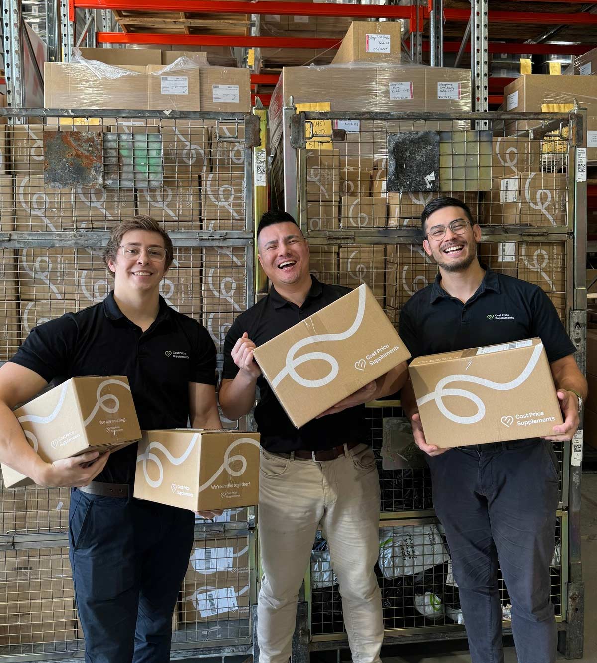 Three men holding boxes in a warehouse setting