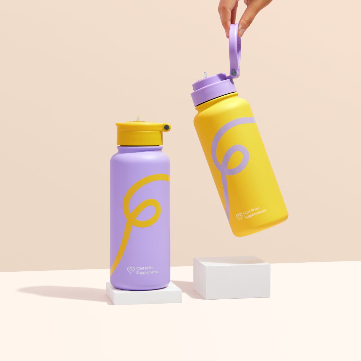 Purple and Yellow water bottles on a white block in front of a peach background
