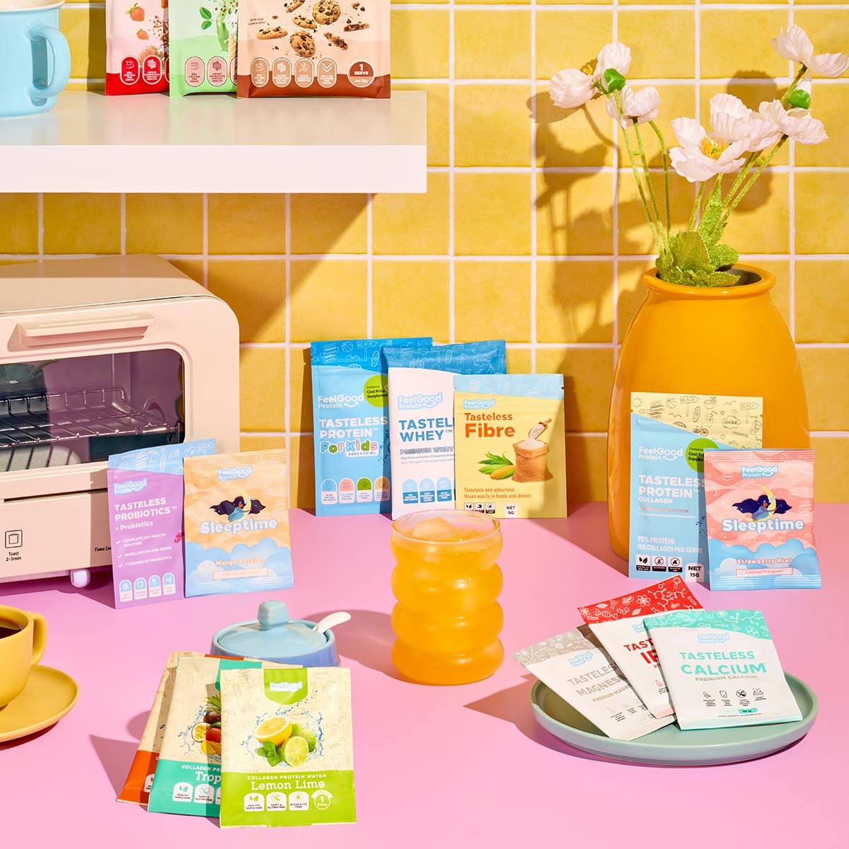 Assorted health and wellness products on a pink surface with a yellow tiled wall background.