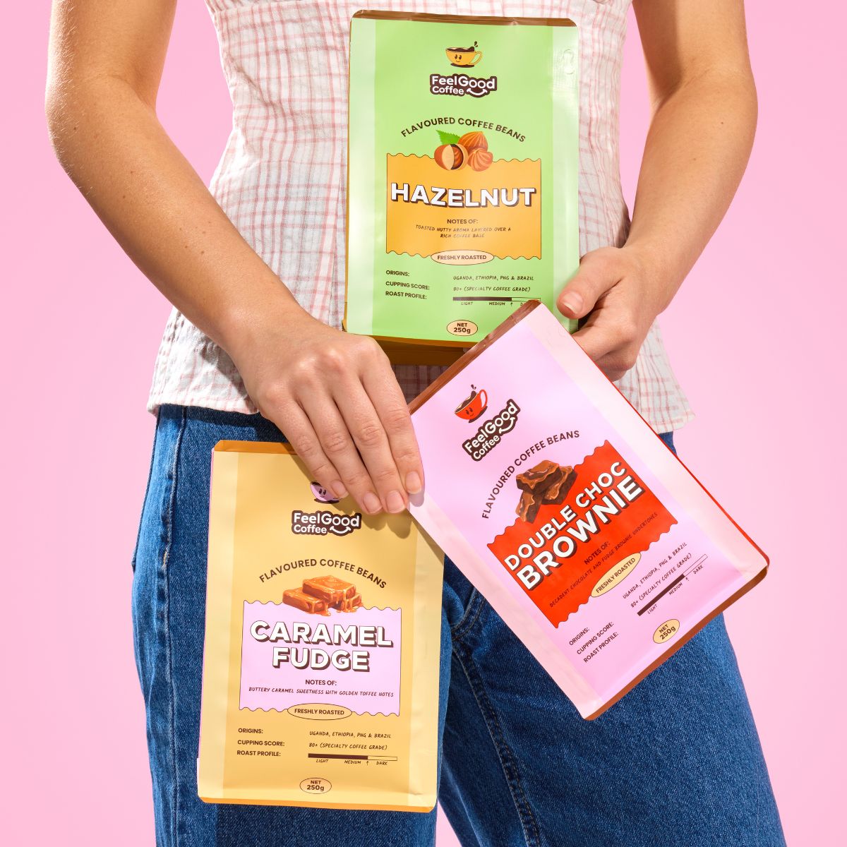 3 Flavoured Coffee Beans by Feel Good Coffee being held up against a pink background