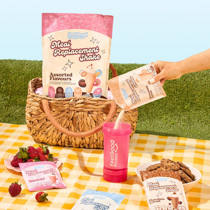 Meal Replacement Shake Assorted Flavours by Feel Good Protein in a picnic basket next to Cinnamon Donut shake being poured into a Feel Good Shaker Bottle. 
