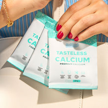 Three packets of 'Tasteless Calcium' supplement held by a person with red nail polish.