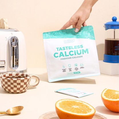 Tasteless Calcium by Feel Good Protein surrounded by breakfast, coffee, toast and oranges