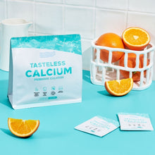 Tasteless Calcium by Feel Good Protein next to a basket of oranges and Tasteless Calcium sachets