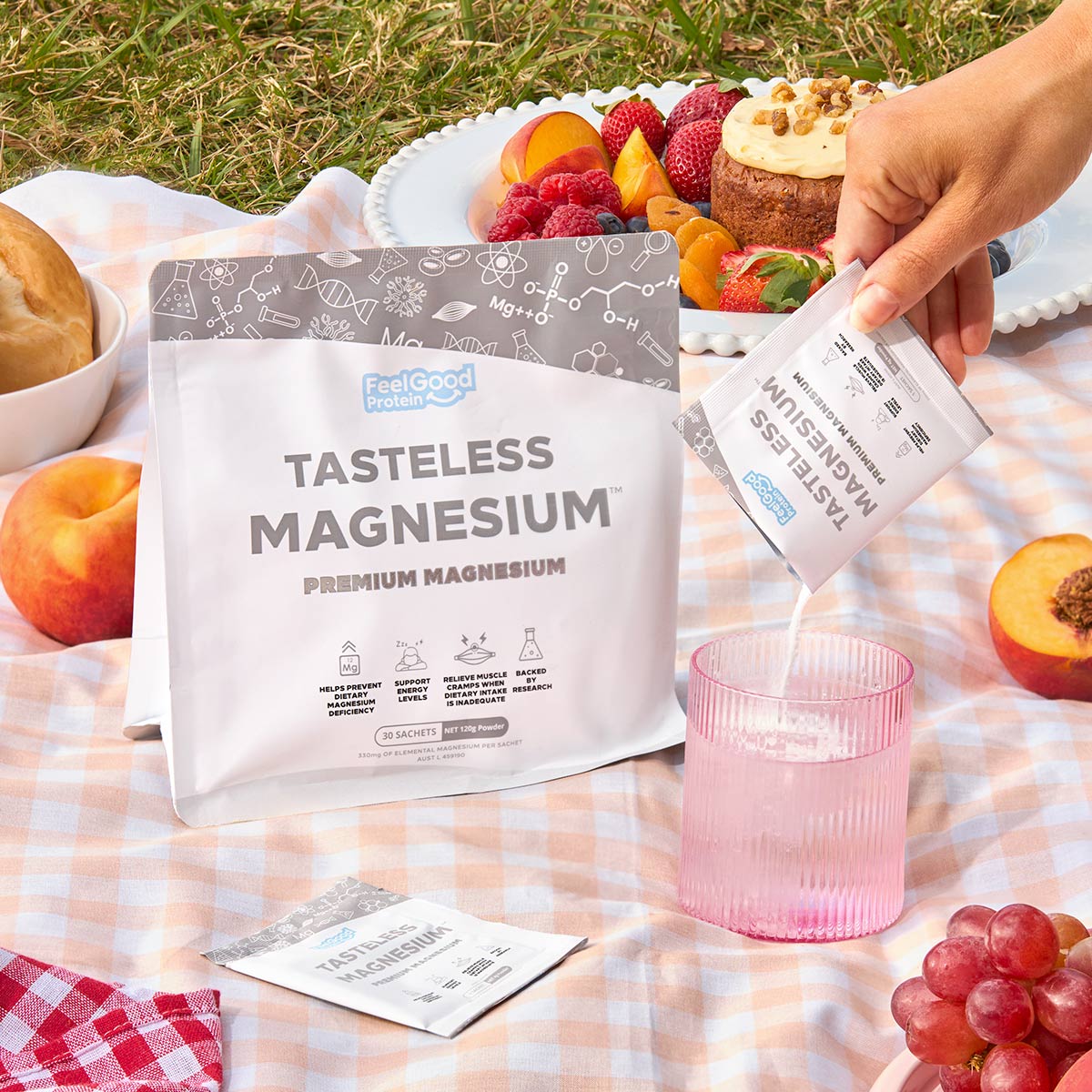 Tasteless Magnesium by Feel Good Protein on a Picnic rug surrounded by peaches with a Tasteless Magnesium sachet poured into a glass of water