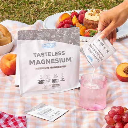 Tasteless Magnesium by Feel Good Protein on a Picnic rug surrounded by peaches with a Tasteless Magnesium sachet poured into a glass of water