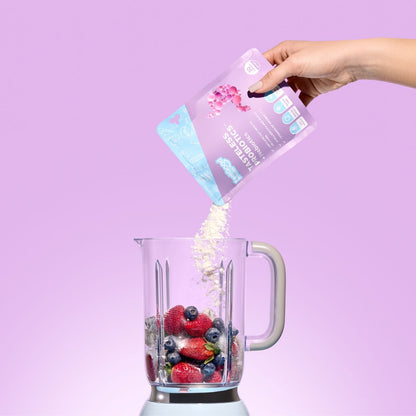 Tasteless Probiotics by Feel Good Protein being added to berries in a blender against a purple background