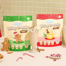Gingerbread Cookie and Eggnog Whey Protein on a kitchen benchtop surrounded by candy canes, and gingerbreads