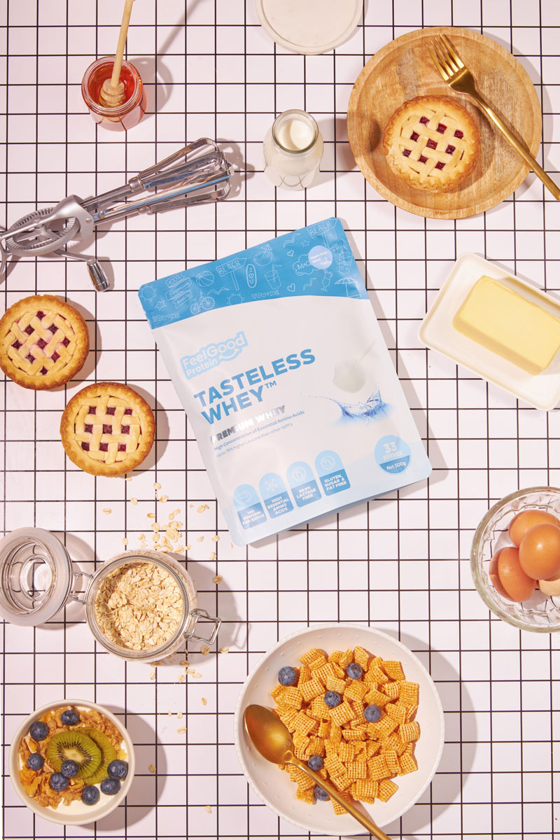 Tasteless Whey protein package on a checkered tablecloth with breakfast items around