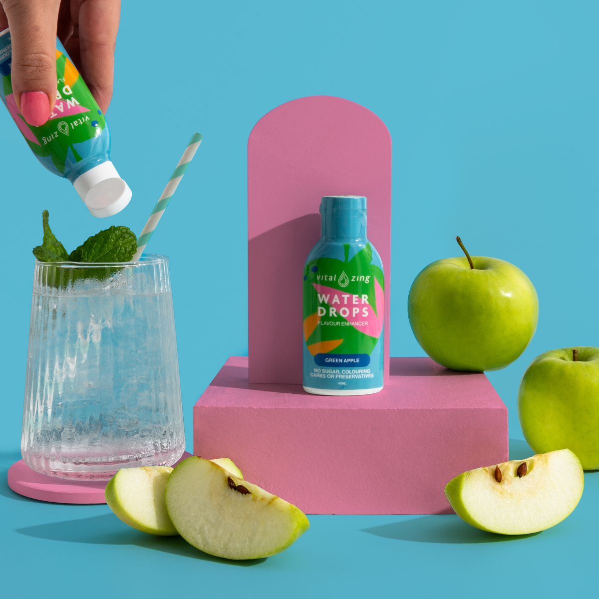 Green Apple Water Drops by Vital Zing surrounded by green apples on a blue background